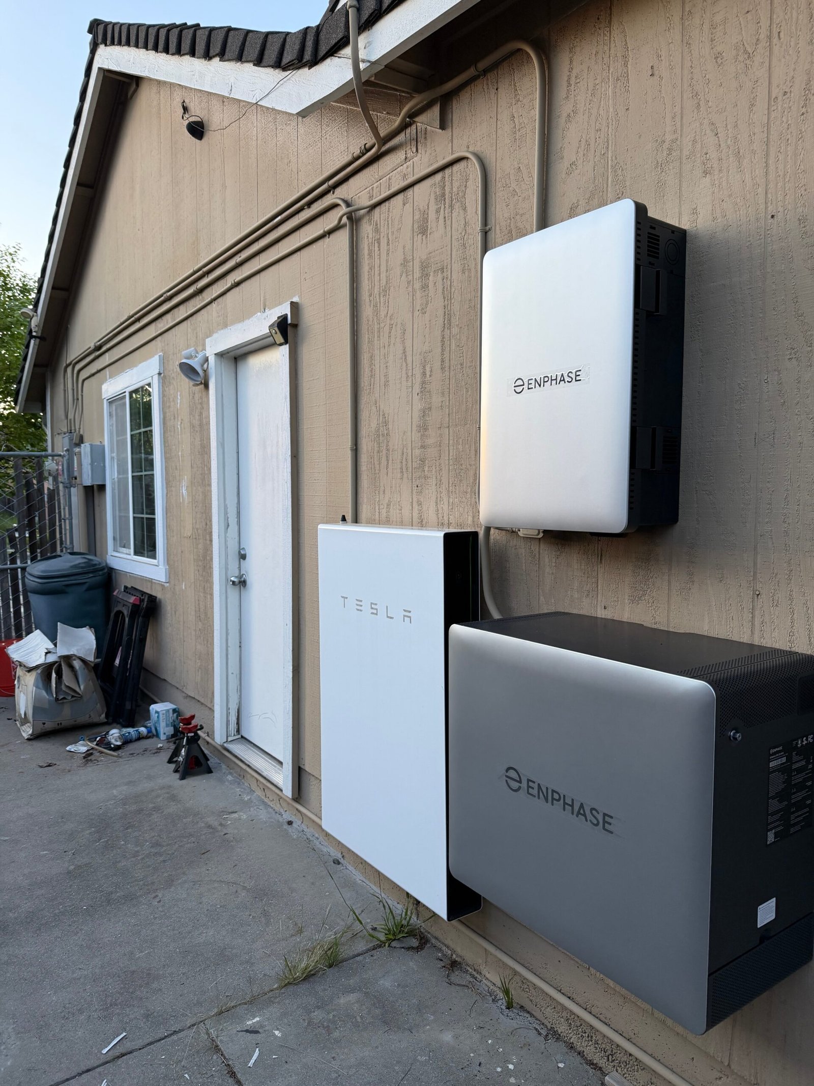 Tesla Powerwall and Enphase battery storage system mounted on an exterior wall