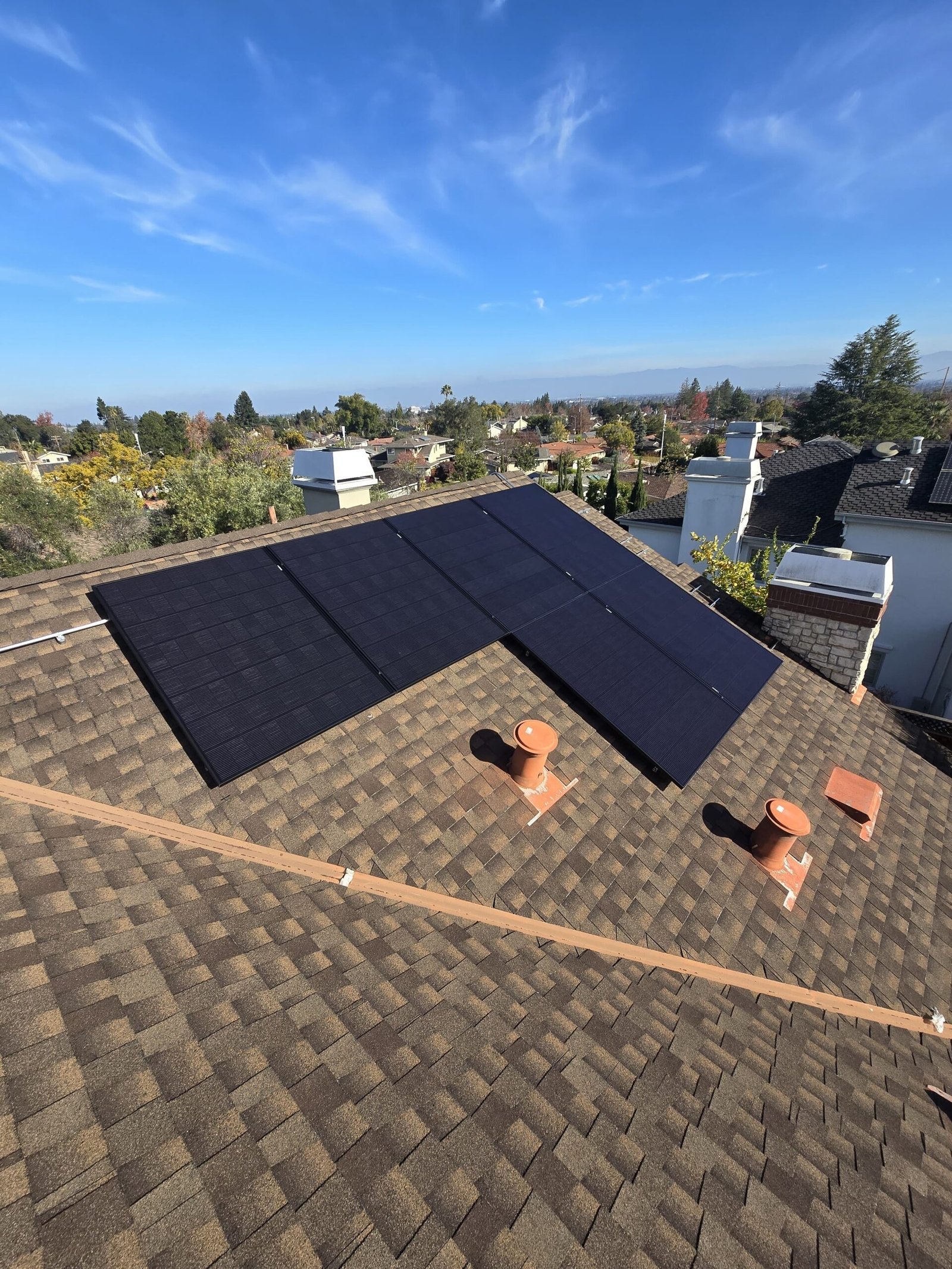 Aerial view of a rooftop solar array with a panoramic Bay Area view in the background