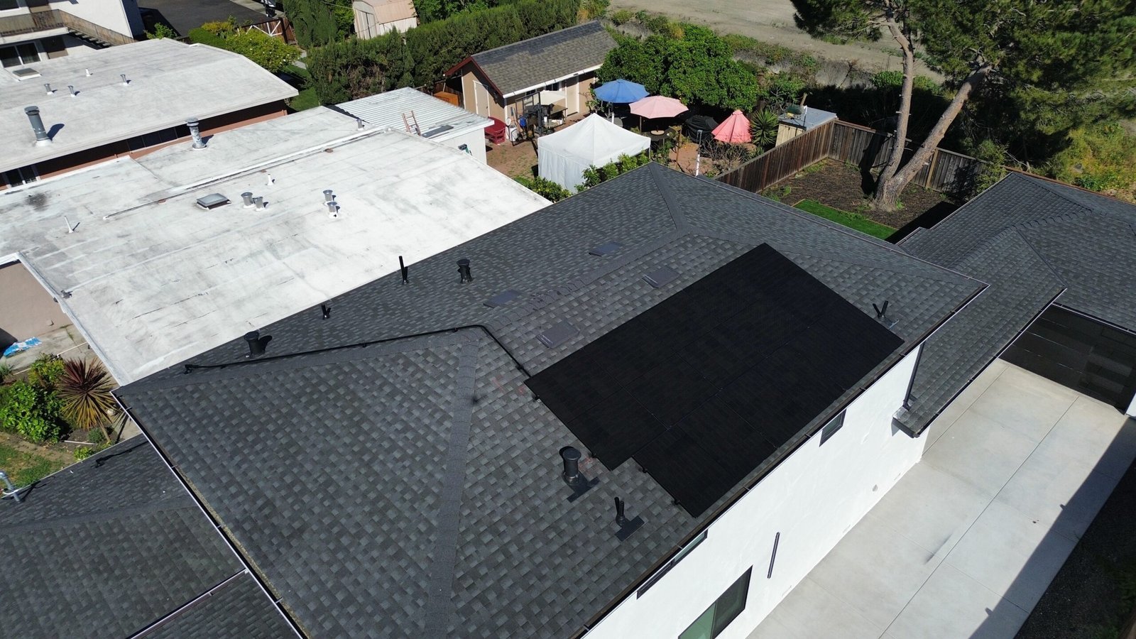 Aerial view of a dark rooftop solar array on a multi-roof property