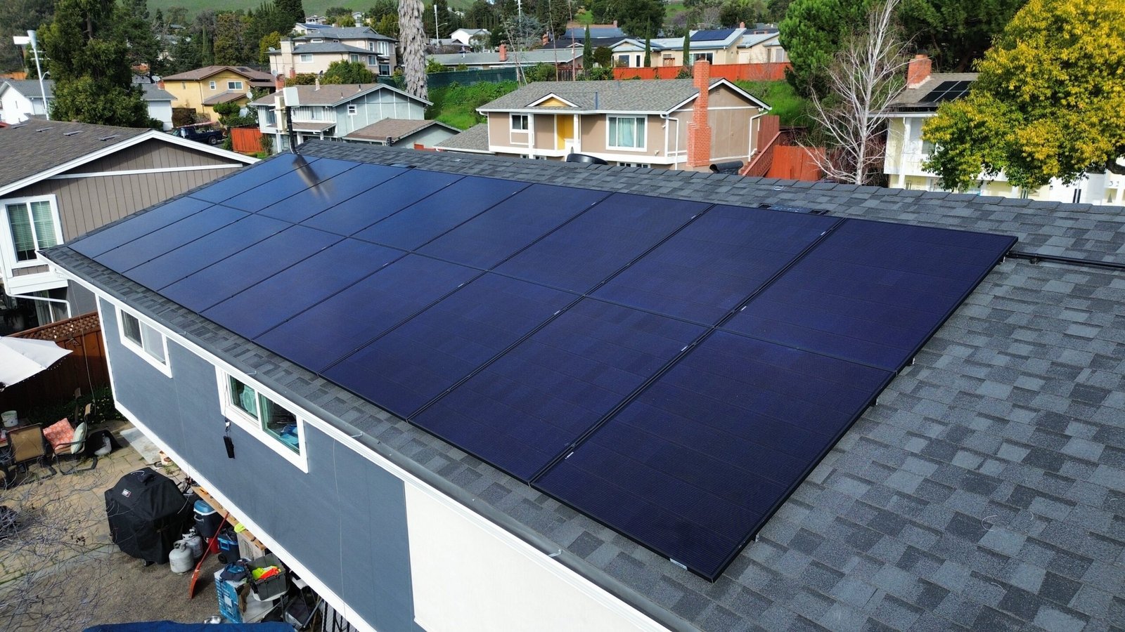 Aerial view of a rooftop solar installation on a hillside home overlooking neighboring rooftops